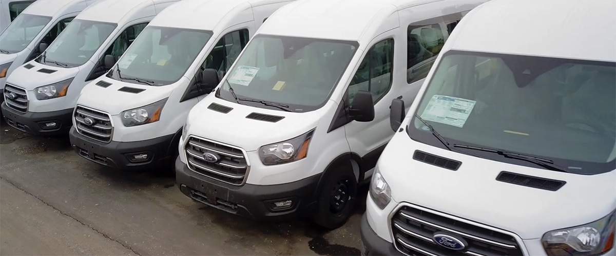 Row of white Ford Transit vans for sale at Master's Transportation - Denver